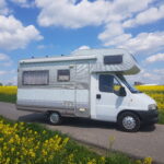 Zdjęcie Kampera Fiat Ducato II Dethleffs stojącego na drodze, łące kwiatowej