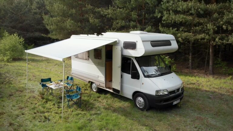 Zdjęcie Kampera Fiat Ducato II Dethleffs z rozłożoną markizą stojącego w lesie