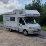 Przód kampera Fiat Ducato II Hymer Struś stojący na drodze w tle las