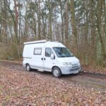 Fiat Peugeot Boxer CamperVan na drodze w lesie jesienią