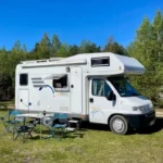 Przód i bok kampera Hymer 2.8 "Koala" na łące w lesie wśród drzew