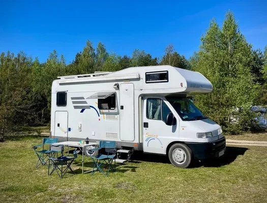 Przód i bok kampera Hymer 2.8 "Koala" na łące w lesie wśród drzew