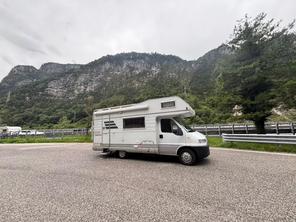 Kamper na wynajem Hymer Żółwik na żwirowej drodze w tle widok gór