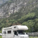Kamper na wynajem Hymer Żółwik na żwirowej drodze w tle widok gór