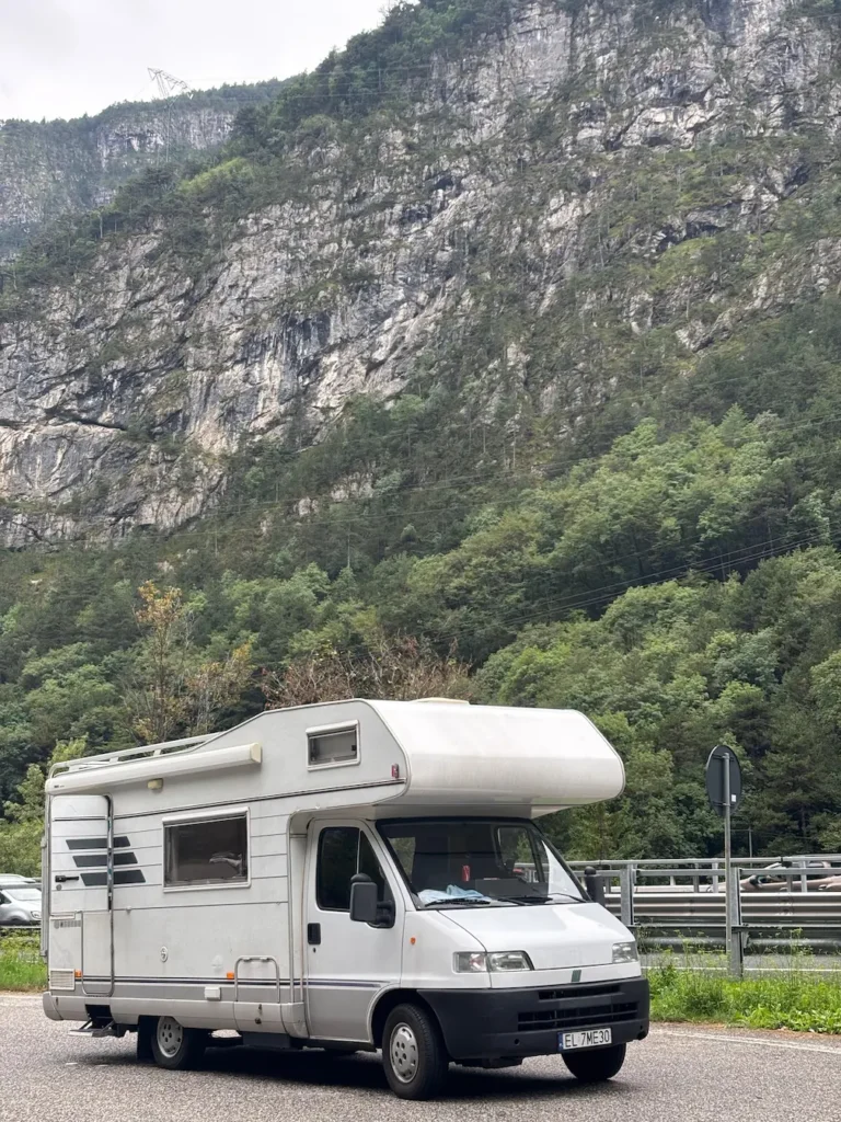 Kamper na wynajem Hymer Żółwik na żwirowej drodze w tle widok gór