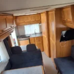 Wnętrze kampera na wynajem Hymer Żółwik zlew, kuchenka, miejsca siedzące, stolik i tv