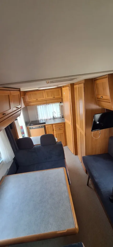 Wnętrze kampera na wynajem Hymer Żółwik zlew, kuchenka, miejsca siedzące, stolik i tv
